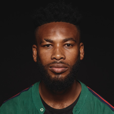 Cara de homem sorridente, vestido de verde.